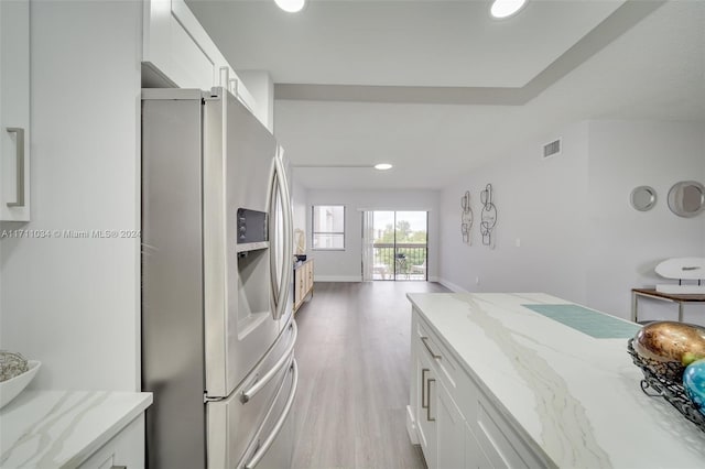 kitchen featuring white cabinetry, stainless steel fridge with ice dispenser, light stone countertops, and light wood-type flooring