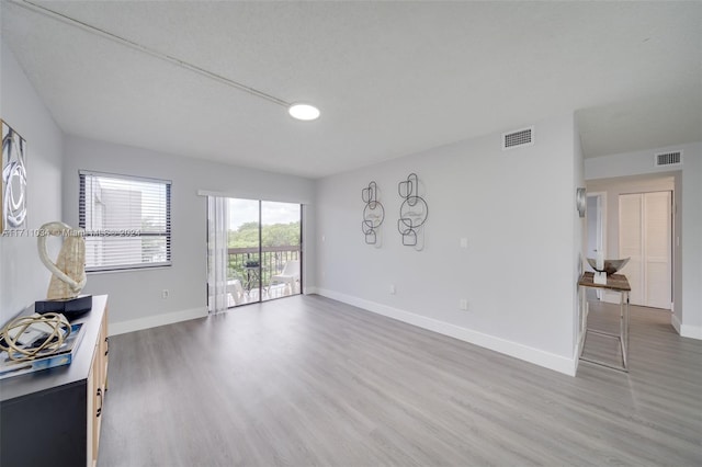 unfurnished living room featuring wood-type flooring and a textured ceiling