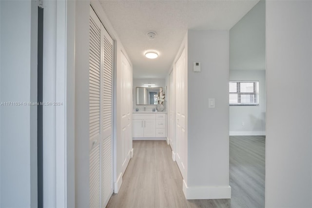 corridor featuring light hardwood / wood-style floors and a textured ceiling