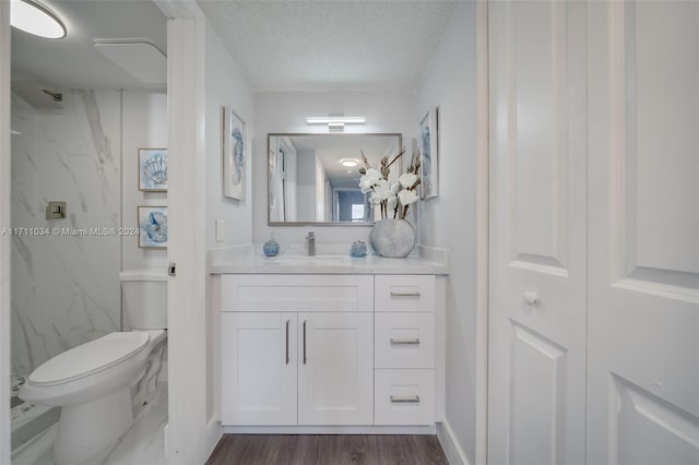 bathroom with a shower, hardwood / wood-style floors, a textured ceiling, toilet, and vanity