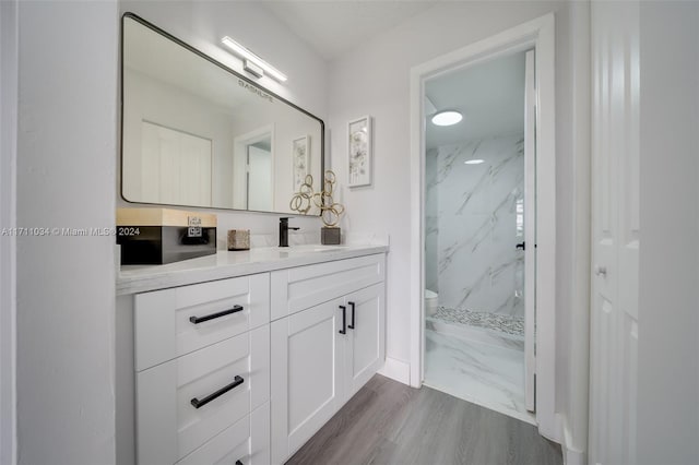 bathroom featuring a tile shower, vanity, hardwood / wood-style flooring, and toilet