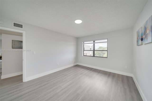 empty room with a textured ceiling and light wood-type flooring