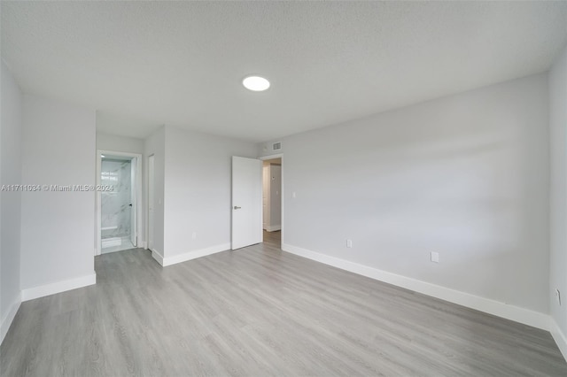 unfurnished room featuring a textured ceiling and light wood-type flooring