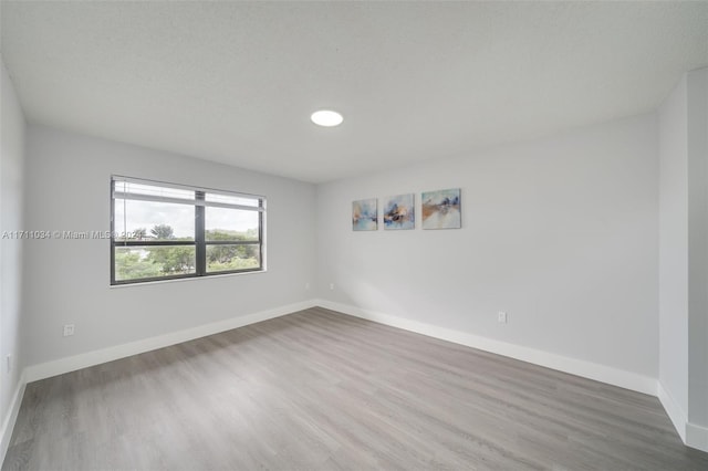 spare room featuring hardwood / wood-style floors and a textured ceiling