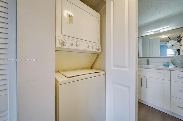 clothes washing area featuring dark hardwood / wood-style floors, a textured ceiling, and stacked washer and clothes dryer