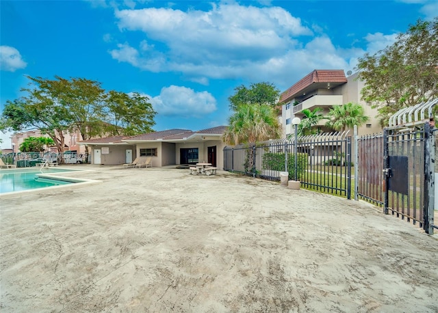 back of property featuring a fenced in pool and a patio