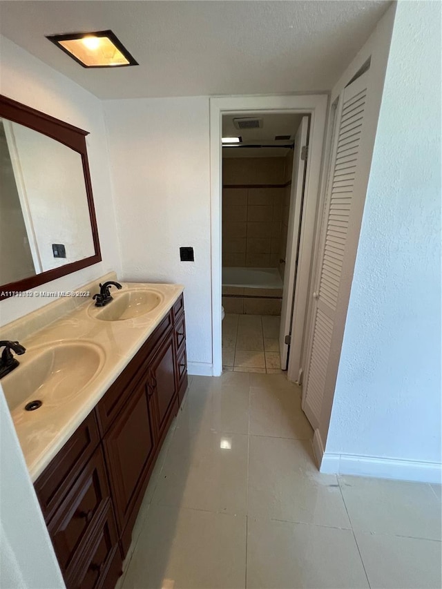 bathroom with tile patterned flooring, vanity, a textured ceiling, and walk in shower