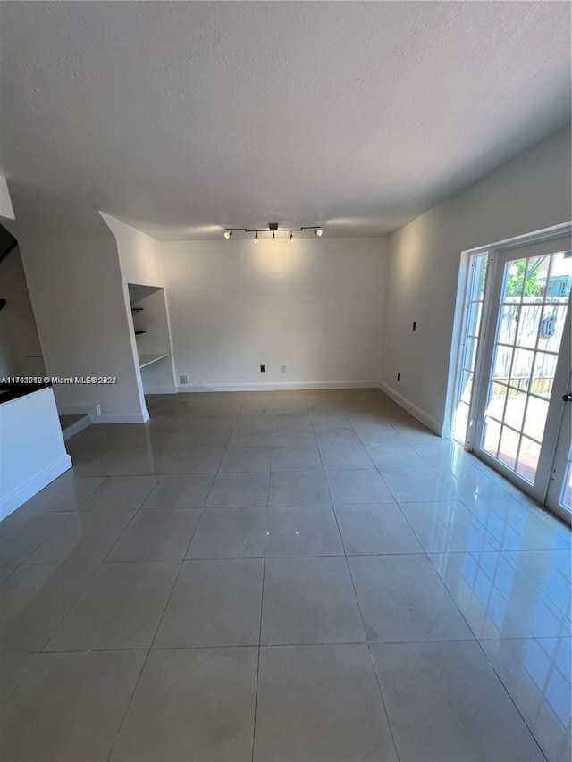 tiled empty room featuring a textured ceiling