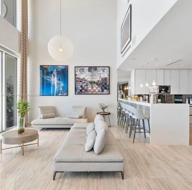 living room featuring light wood-type flooring and a towering ceiling