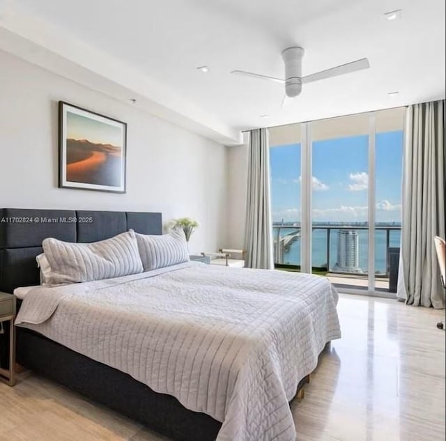 bedroom featuring floor to ceiling windows, access to outside, ceiling fan, a water view, and multiple windows