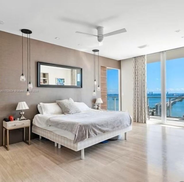 bedroom featuring access to exterior, ceiling fan, a water view, and multiple windows