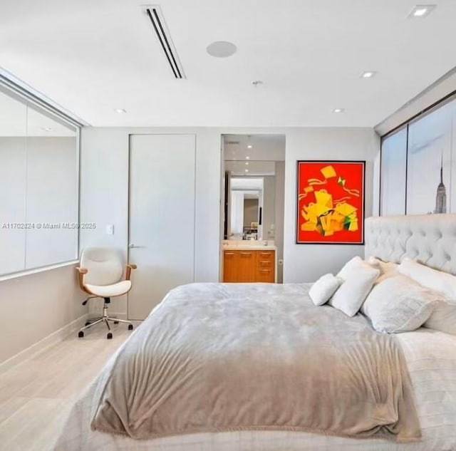 bedroom featuring light hardwood / wood-style flooring and ensuite bath