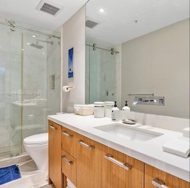 bathroom featuring tile patterned flooring, vanity, toilet, and a shower with door