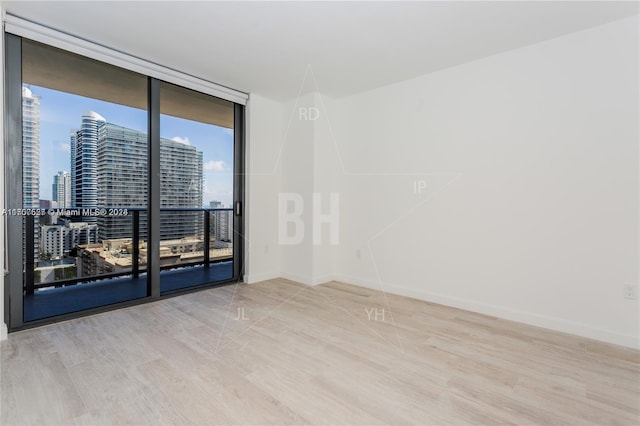 unfurnished room with hardwood / wood-style floors and a wall of windows