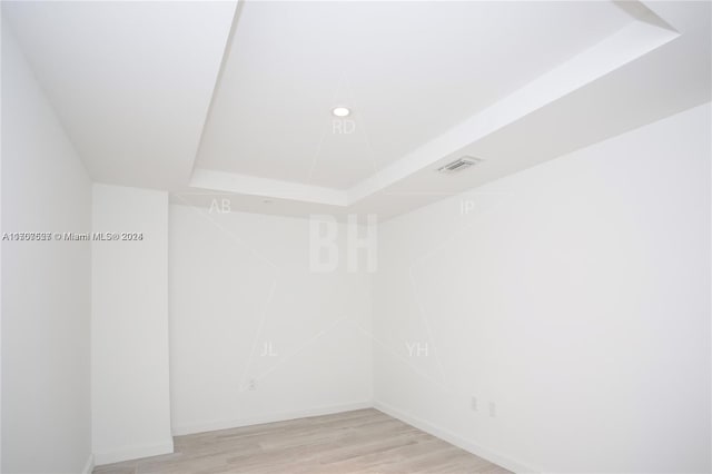 empty room featuring light hardwood / wood-style floors and a tray ceiling