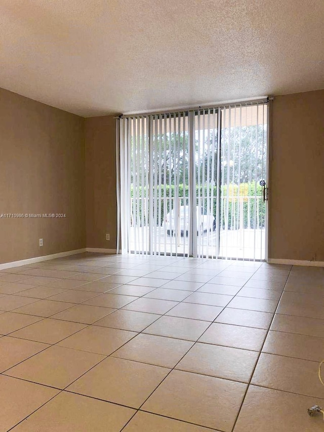 tiled empty room with a textured ceiling and a wealth of natural light