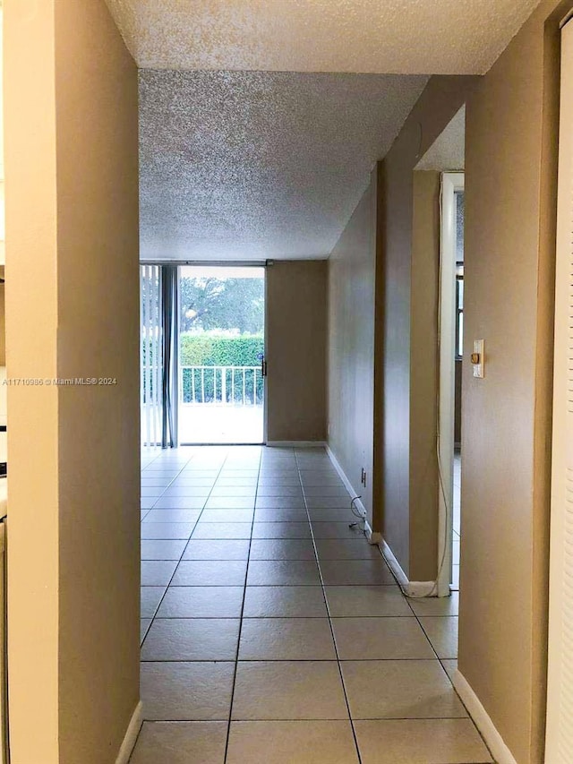 hallway with floor to ceiling windows, light tile patterned floors, and a textured ceiling