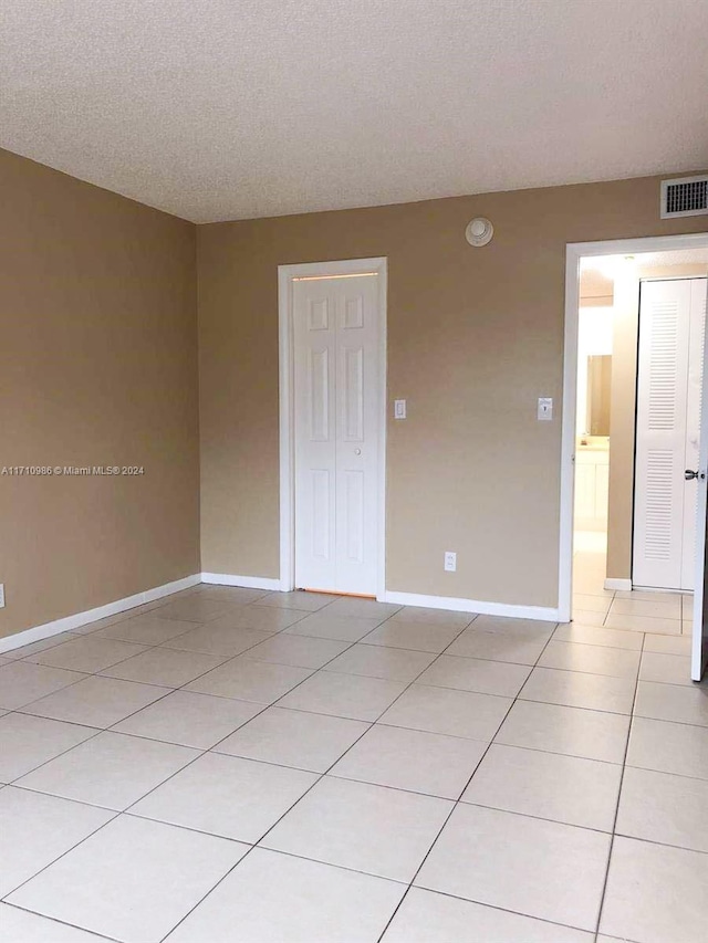 empty room with light tile patterned floors and a textured ceiling