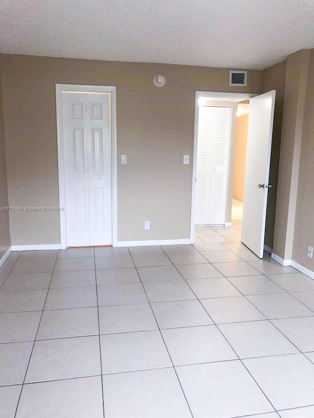 unfurnished room with light tile patterned floors and a textured ceiling