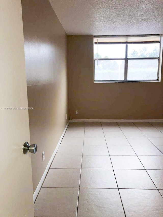 spare room featuring a textured ceiling and light tile patterned flooring