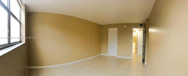 tiled empty room with vaulted ceiling