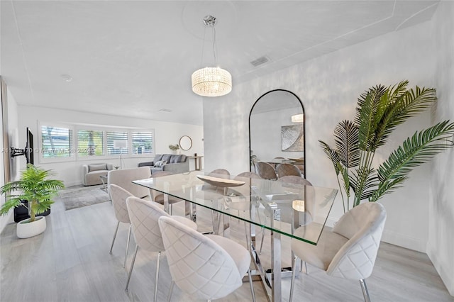 dining area with light hardwood / wood-style floors and an inviting chandelier