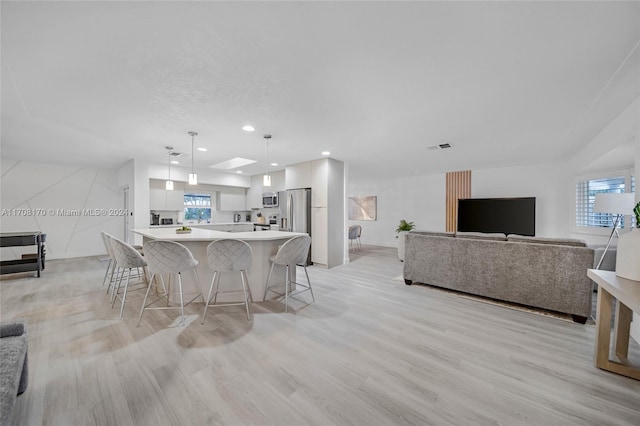 kitchen featuring a kitchen bar, decorative light fixtures, a spacious island, and a healthy amount of sunlight