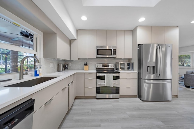 kitchen with light hardwood / wood-style floors, plenty of natural light, stainless steel appliances, and sink