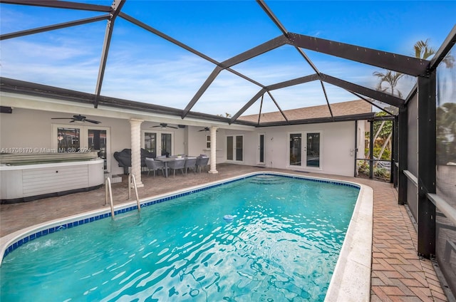 view of swimming pool with french doors, ceiling fan, glass enclosure, a patio area, and a hot tub