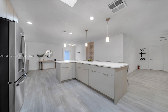 kitchen with white cabinets, ceiling fan, light wood-type flooring, decorative light fixtures, and stainless steel refrigerator