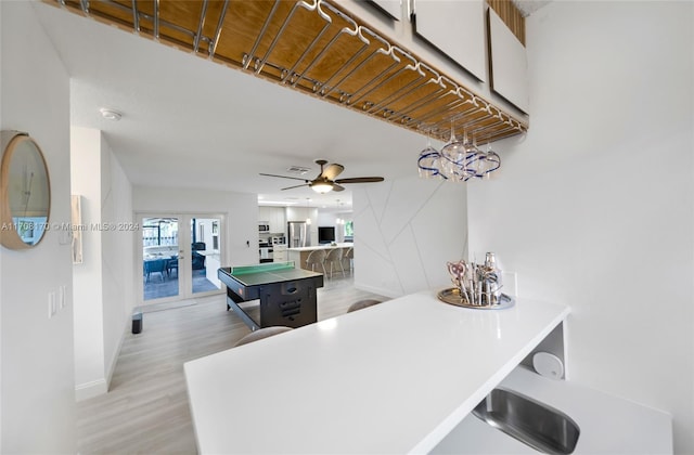 kitchen with stainless steel appliances, ceiling fan, light hardwood / wood-style flooring, a center island, and white cabinetry