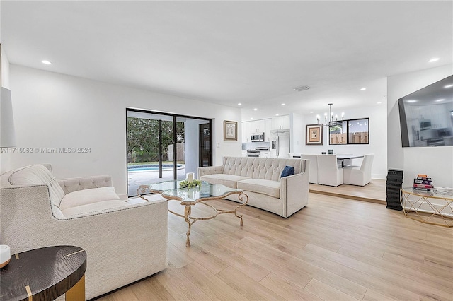 living room with light hardwood / wood-style floors and an inviting chandelier