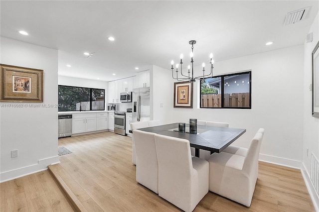 dining room with light hardwood / wood-style floors and an inviting chandelier