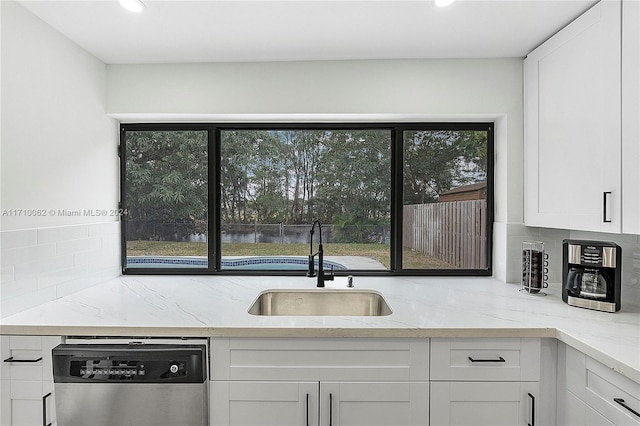 kitchen featuring light stone countertops, sink, stainless steel dishwasher, backsplash, and white cabinets