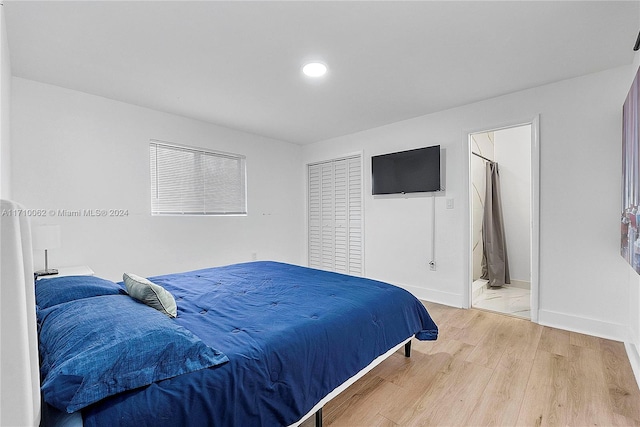 bedroom with hardwood / wood-style flooring, ensuite bath, and a closet