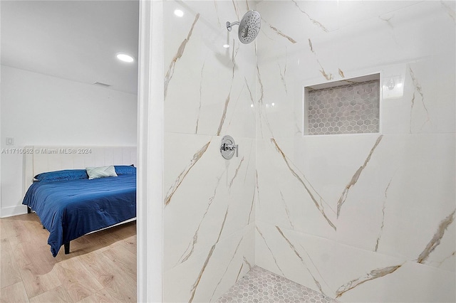 bathroom with a tile shower and wood-type flooring