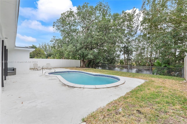 view of swimming pool with a yard, a patio, and a water view