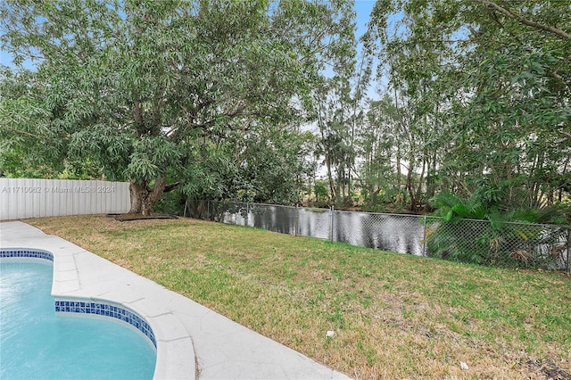 view of yard with a fenced in pool and a water view