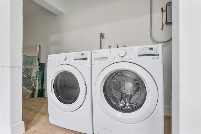 laundry room with washing machine and dryer and light wood-type flooring