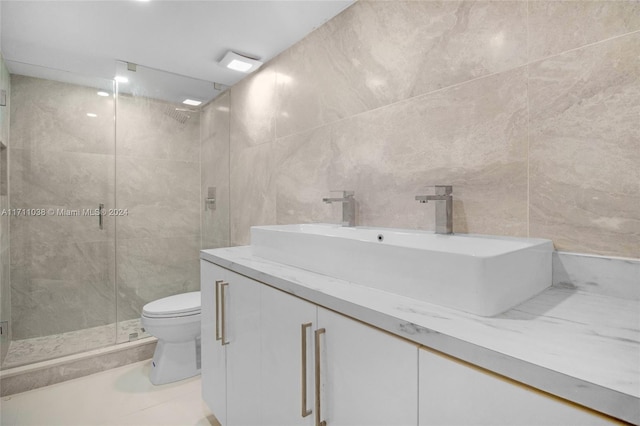 bathroom featuring tile patterned flooring, an enclosed shower, toilet, vanity, and tile walls