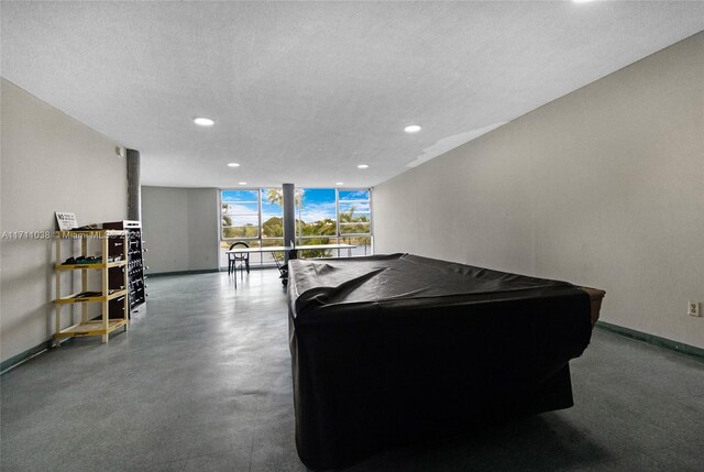 game room with a wall of windows, a textured ceiling, and pool table