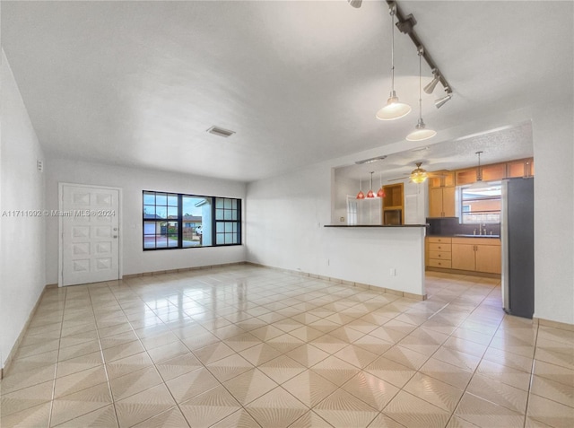 unfurnished living room featuring ceiling fan, sink, rail lighting, and light tile patterned floors