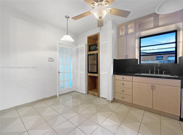 kitchen featuring decorative backsplash, black microwave, sink, light tile patterned floors, and decorative light fixtures