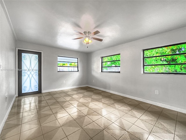 tiled empty room featuring ceiling fan