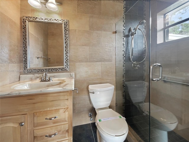 bathroom featuring vanity, toilet, a shower with shower door, and tile walls