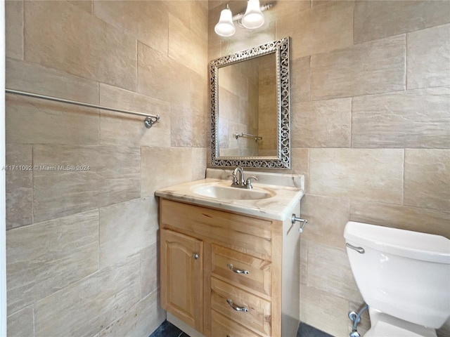 bathroom featuring vanity, tile walls, and toilet