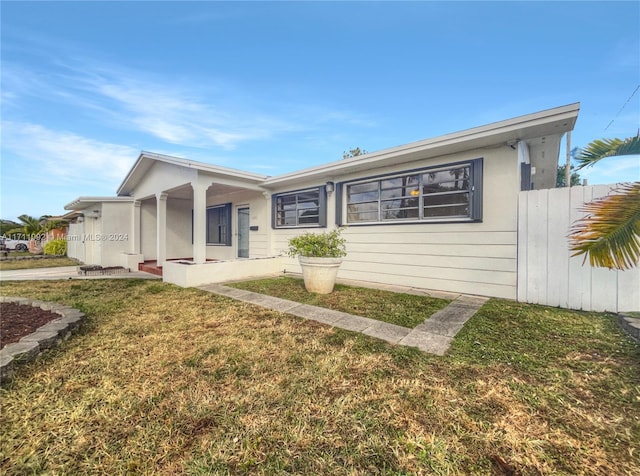 ranch-style house featuring covered porch and a front lawn