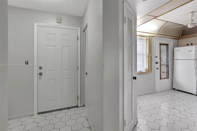 interior space featuring ceiling fan, light tile patterned floors, a textured ceiling, and white refrigerator