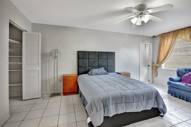 bedroom featuring a textured ceiling, a closet, ceiling fan, and light tile patterned flooring