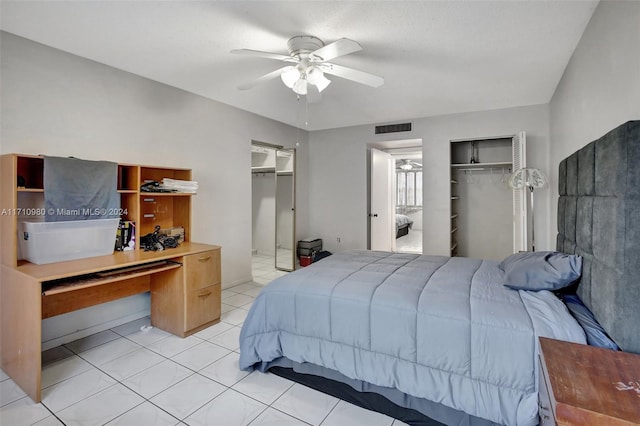 tiled bedroom with ceiling fan and multiple closets